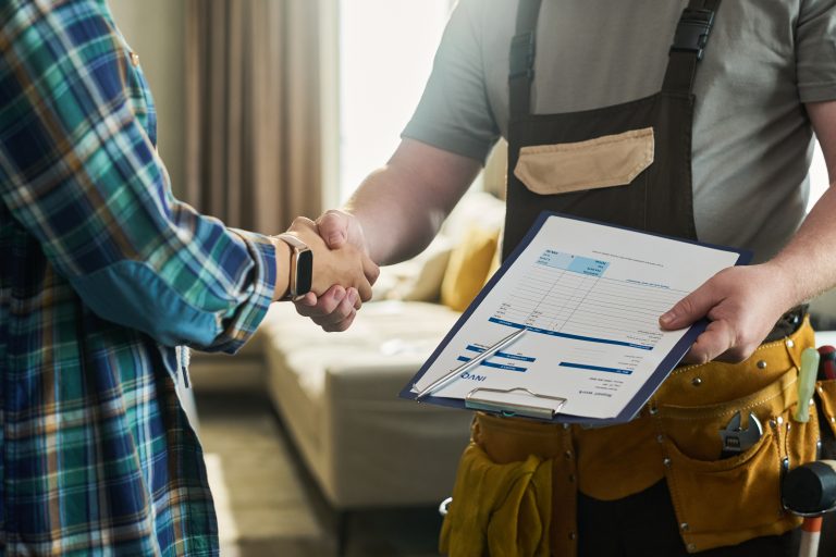 Caucasian Middle Aged Man Shaking Hands with Contractor Holding Invoice